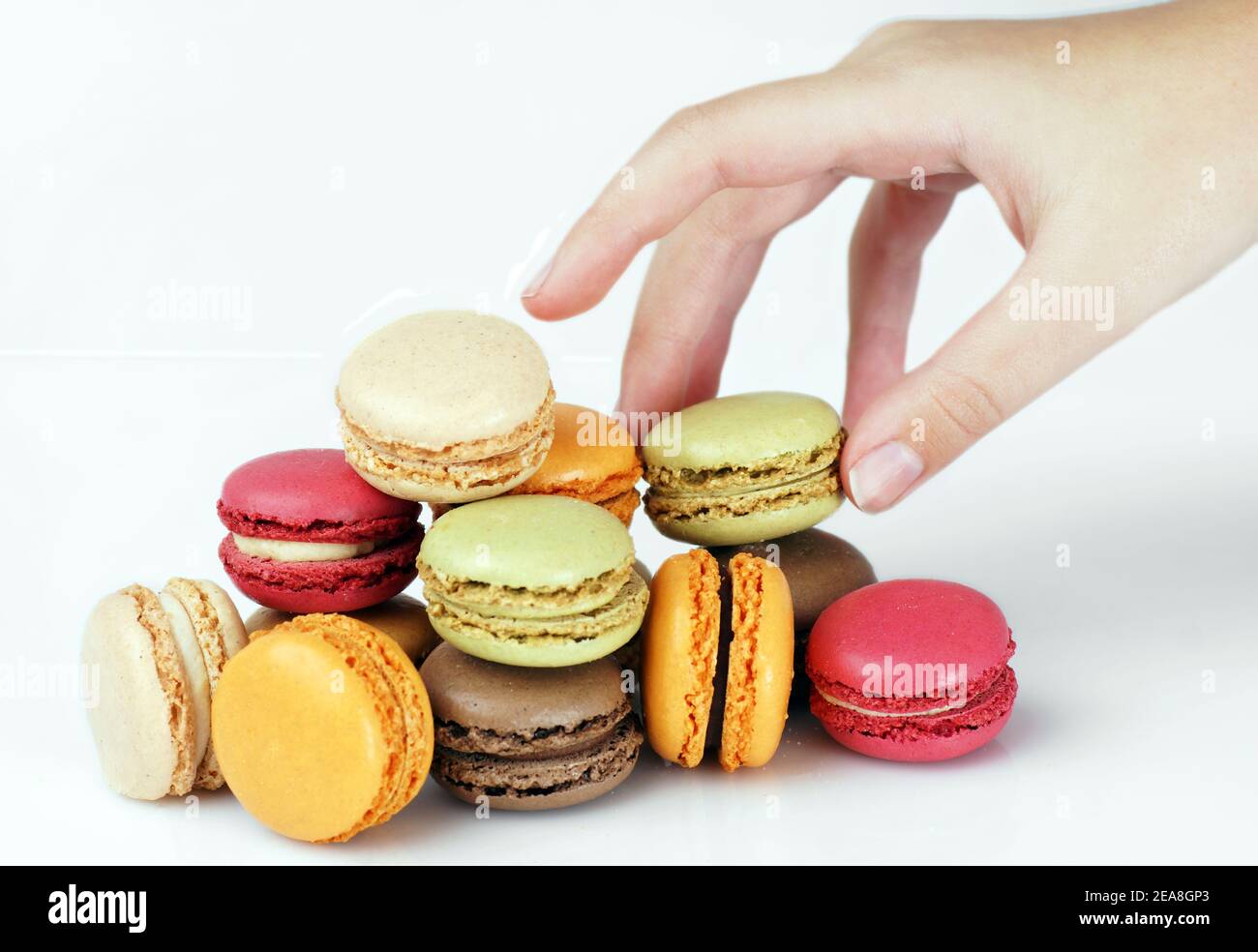 Hand picking up delicious French colorful macarons or macaroons Stock Photo