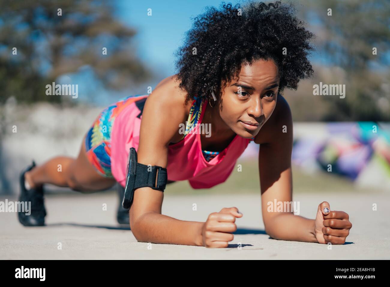 Afro athletic woman doing pushups outdoors. Stock Photo