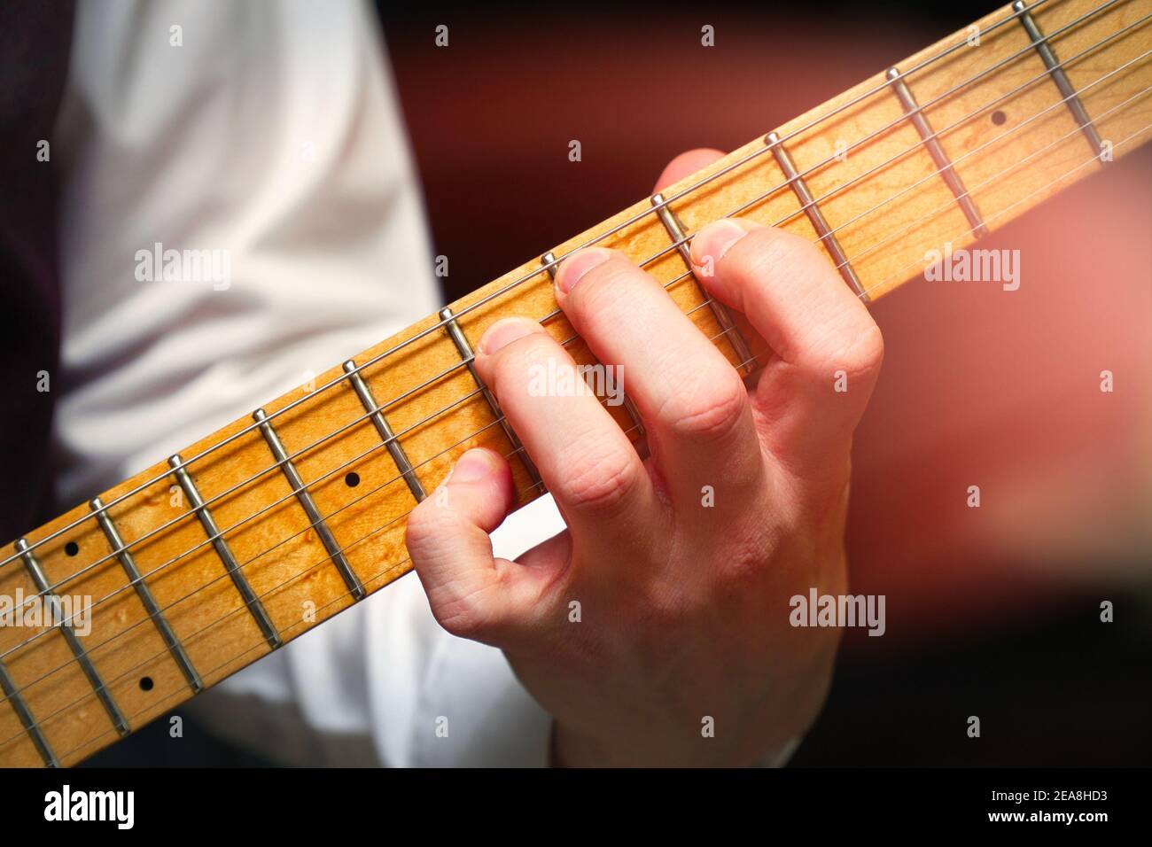 Guitarist's fingers on the neck of a sixstring electric guitar Stock