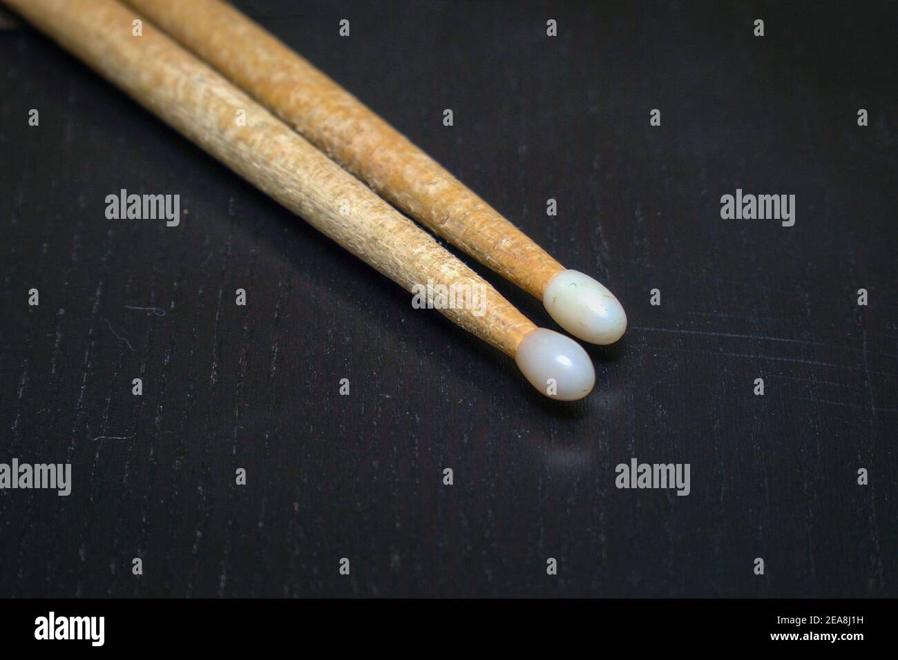 Used wooden drumsticks with white tips on a dark background Stock Photo