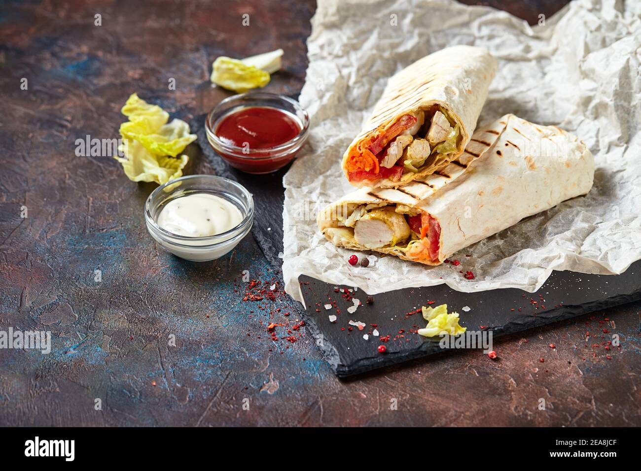 Eastern traditional shawarma with chicken and vegetables, Doner Kebab with sauces on slate. Fast food. Eastern food. Stock Photo