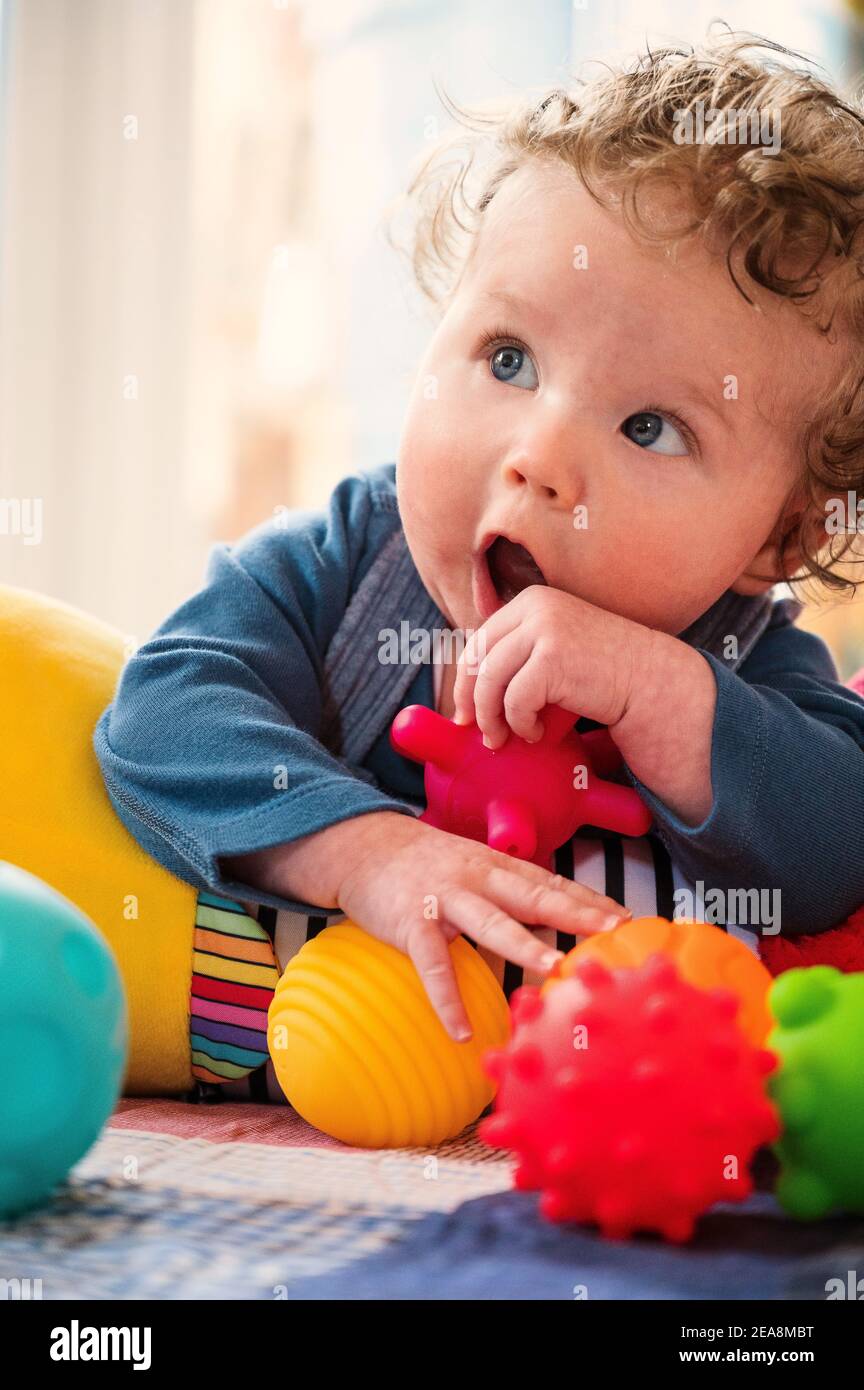 Baby boy using tummy roller and chew balls Stock Photo