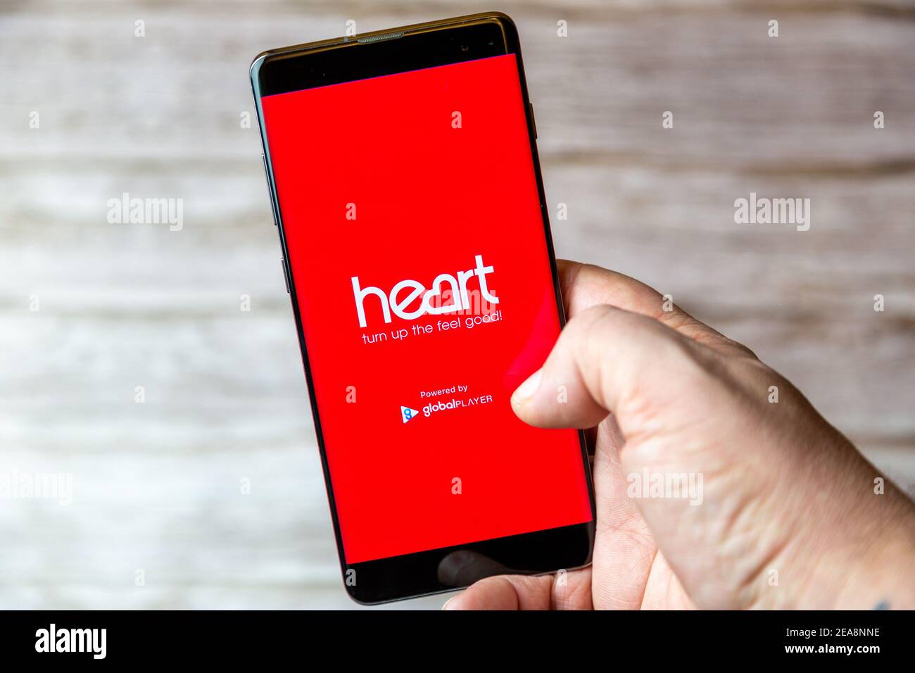 A mobile phone or cell phone being held in a hand with the Heart Radio