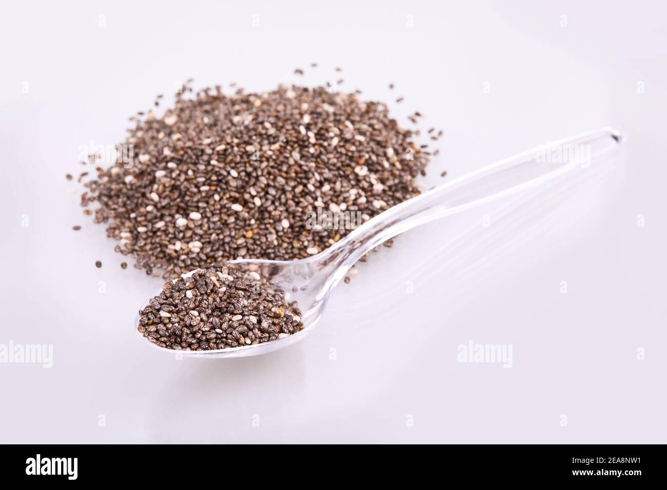 Healthy Chia seeds in transparent glass (plastic) spoon isolated with white background. Top view Stock Photo