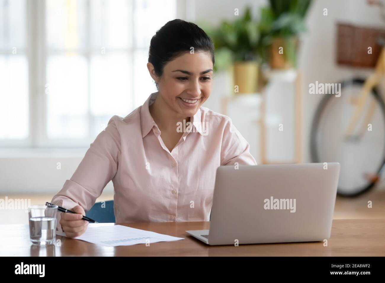 Happy young Indian woman working on laptop at home Stock Photo