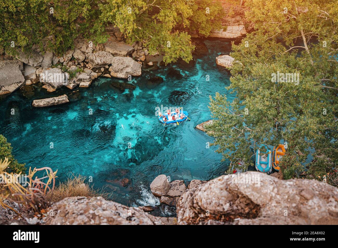 Aerial view of water tourists in a boat during an extreme rafting by a blue mountain river in deep canyon and gorge Stock Photo