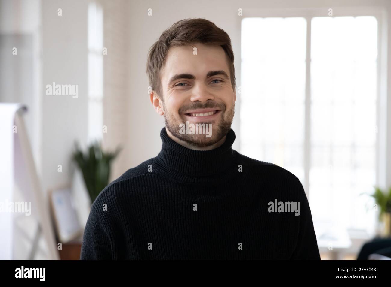 Happy handsome male millennial posing in white interior Stock Photo