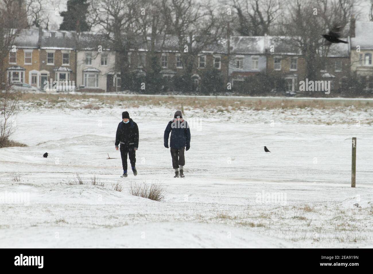 People walk through a snow covered Wanstead Park in Redbridge. Heavy snow and ice has brought disruption to parts of the UK, with London receiving around 5cm of snow. Storm Darcy's strong easterly winds have plummeted temperatures in parts of the UK to below minus one. Stock Photo