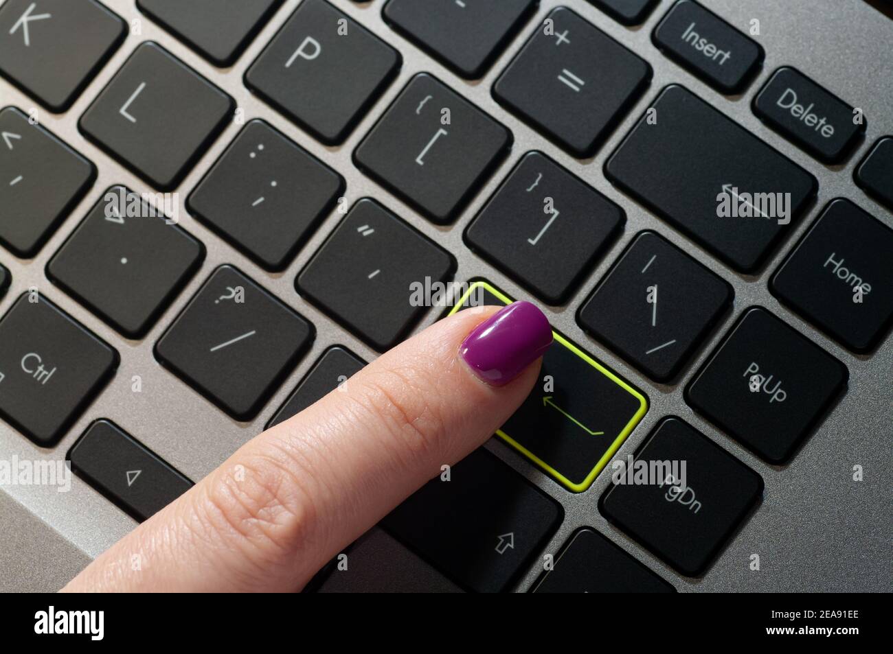 Close up woman's finger pressing enter button on the laptop keyboard. Stock Photo