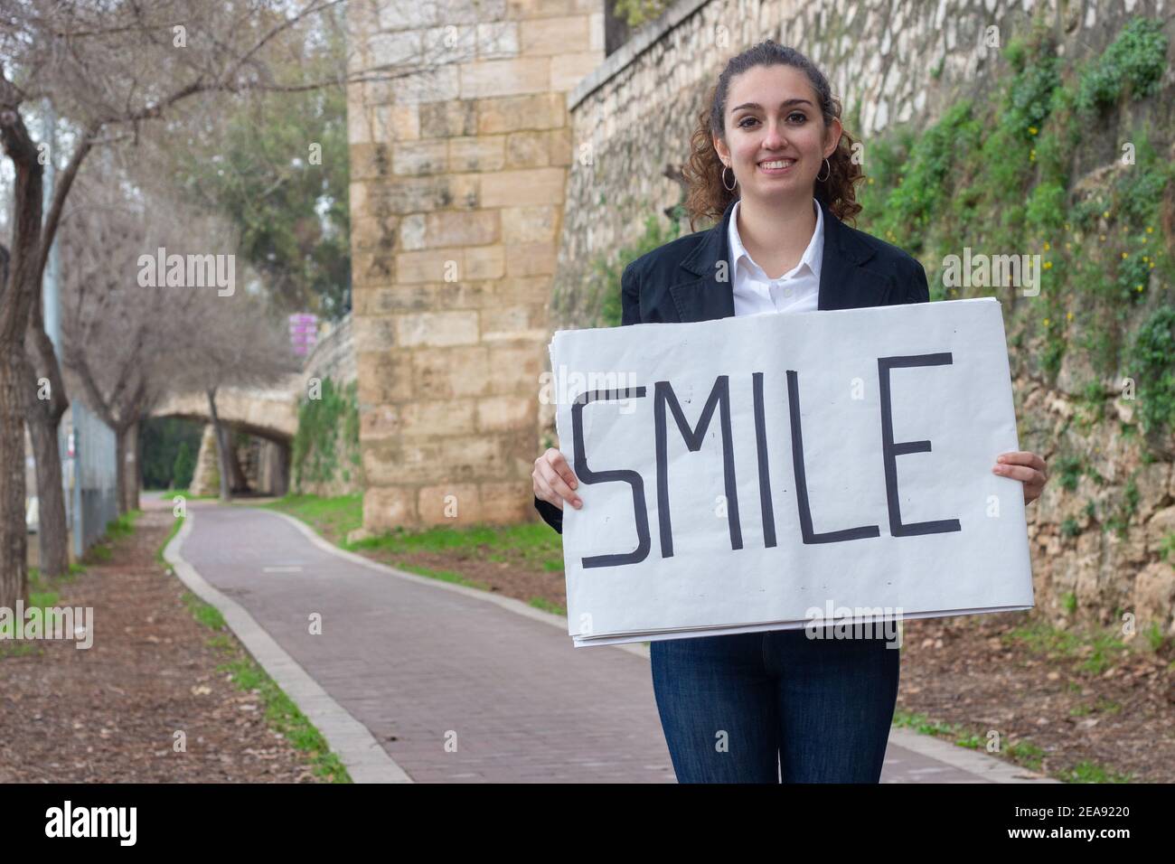 Young female holding a sign saying 'smile' Stock Photo - Alamy