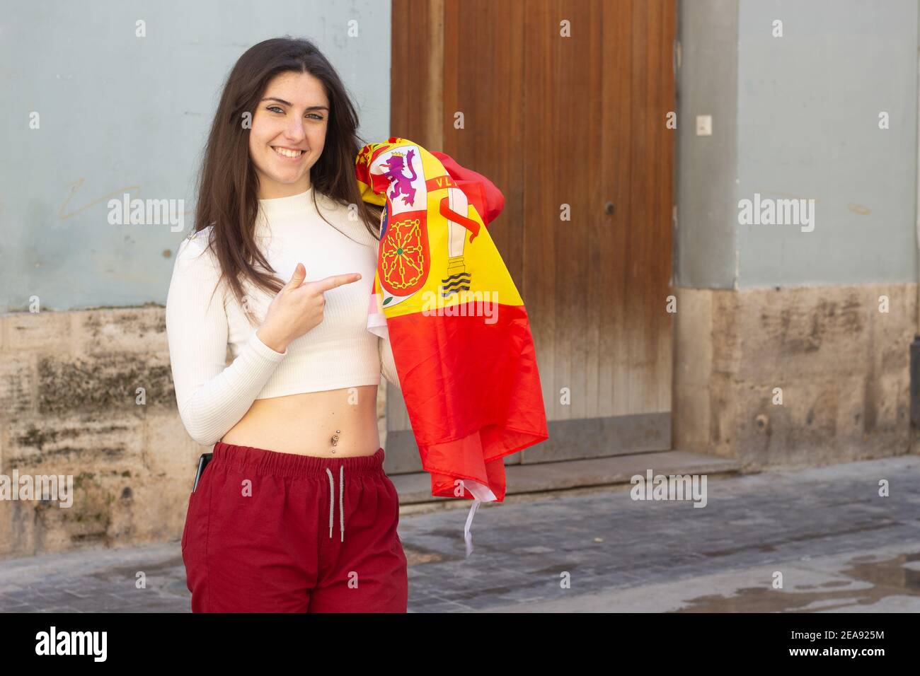 Young lady holding the Spanish flag wearing a crop top and sweatpants