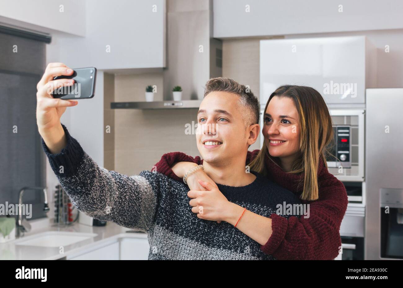 Adorable young couple smiling and taking a selfie with mobile phone at ...