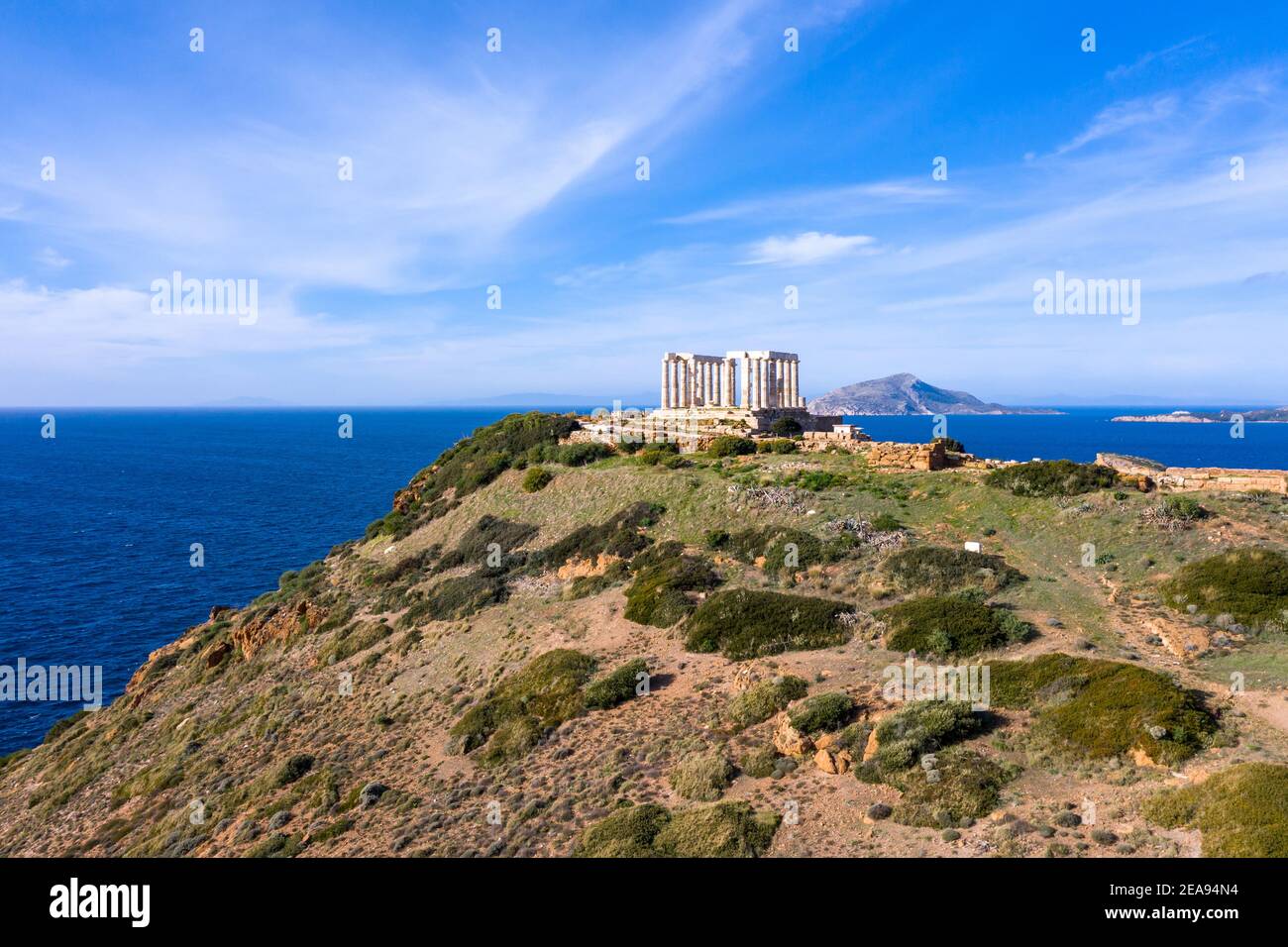 Cape Sounio, Greece. Poseidon temple aerial drone view. Archaeological site of ancient greek ruins up on a hill, Athens Attica. Cloudy blue sky backgr Stock Photo