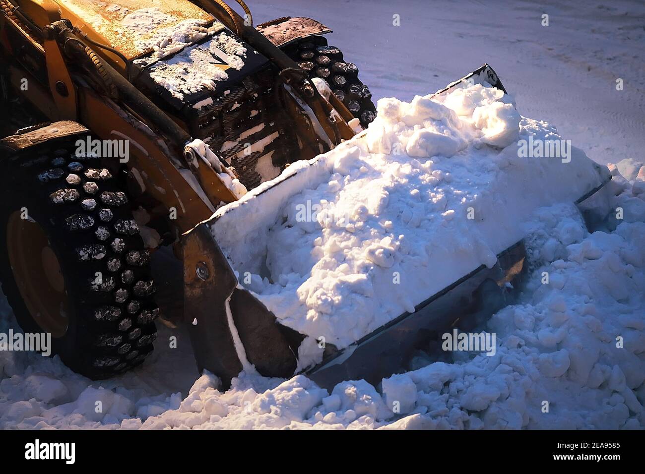 Excavator with a full bucket of snow. Snow removal from city streets at night.  Stock Photo