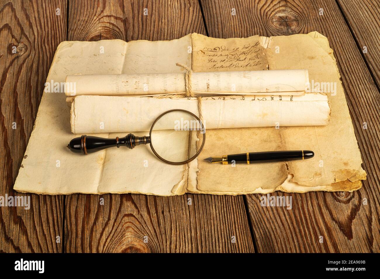 Fountain pen and magnifying glass with old sheets on wood background Stock Photo