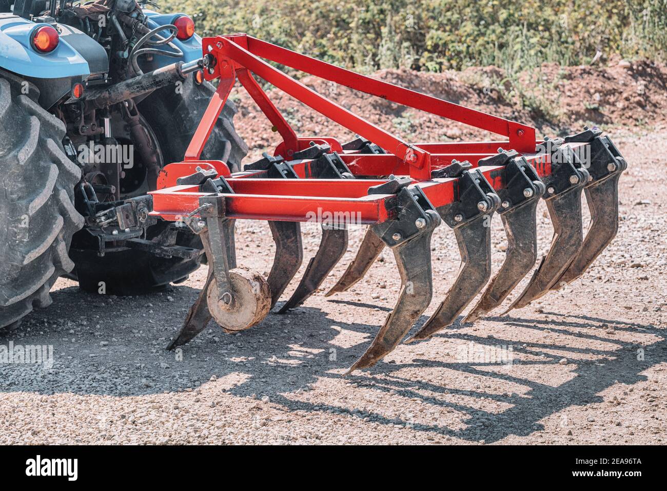 a plow for cultivating the soil is attached to a dusty tractor. Equipment in industry of agriculture Stock Photo