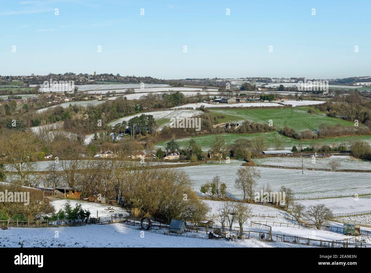 Snow-dusted pastureland, Bybrook Valley and Colerne village, Wiltshire, UK, January. Stock Photo