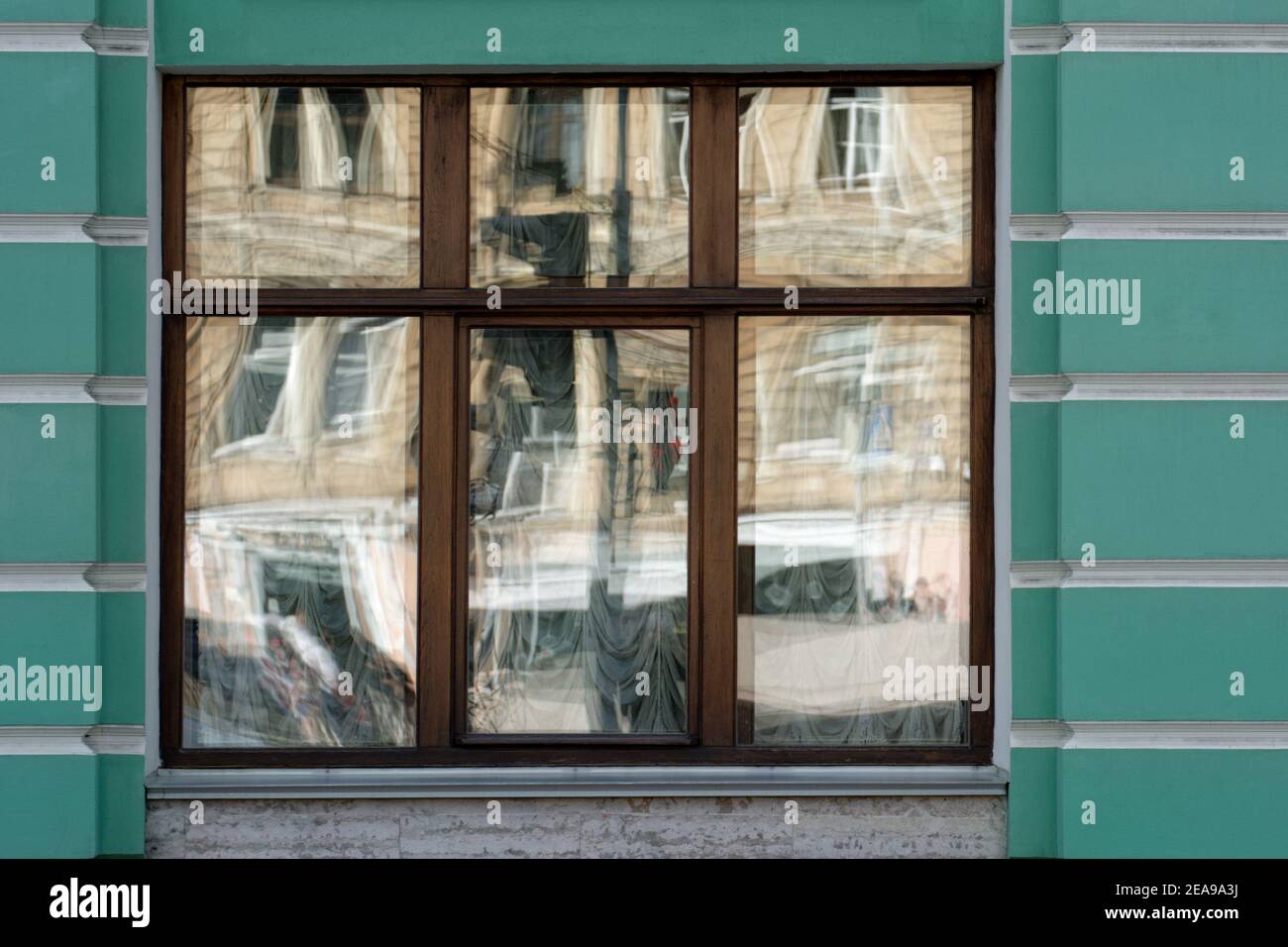 Reflections in the glass of a rectangular window against a green wall. From a series of windows of St. Petersburg. Stock Photo