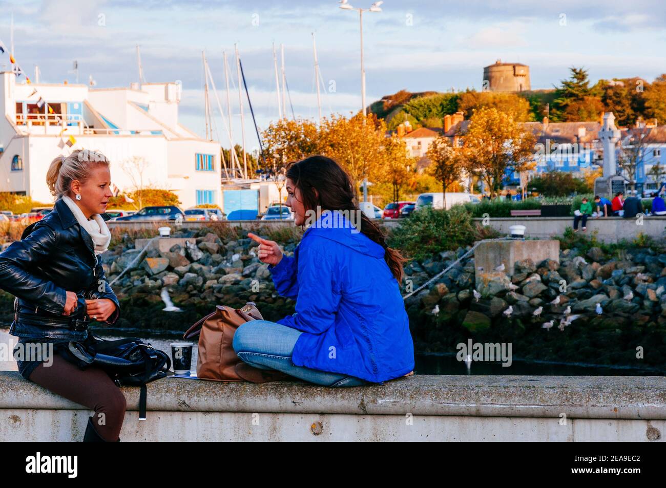 Two young women chat on the boardwalk. Howth Marina. Howth, County