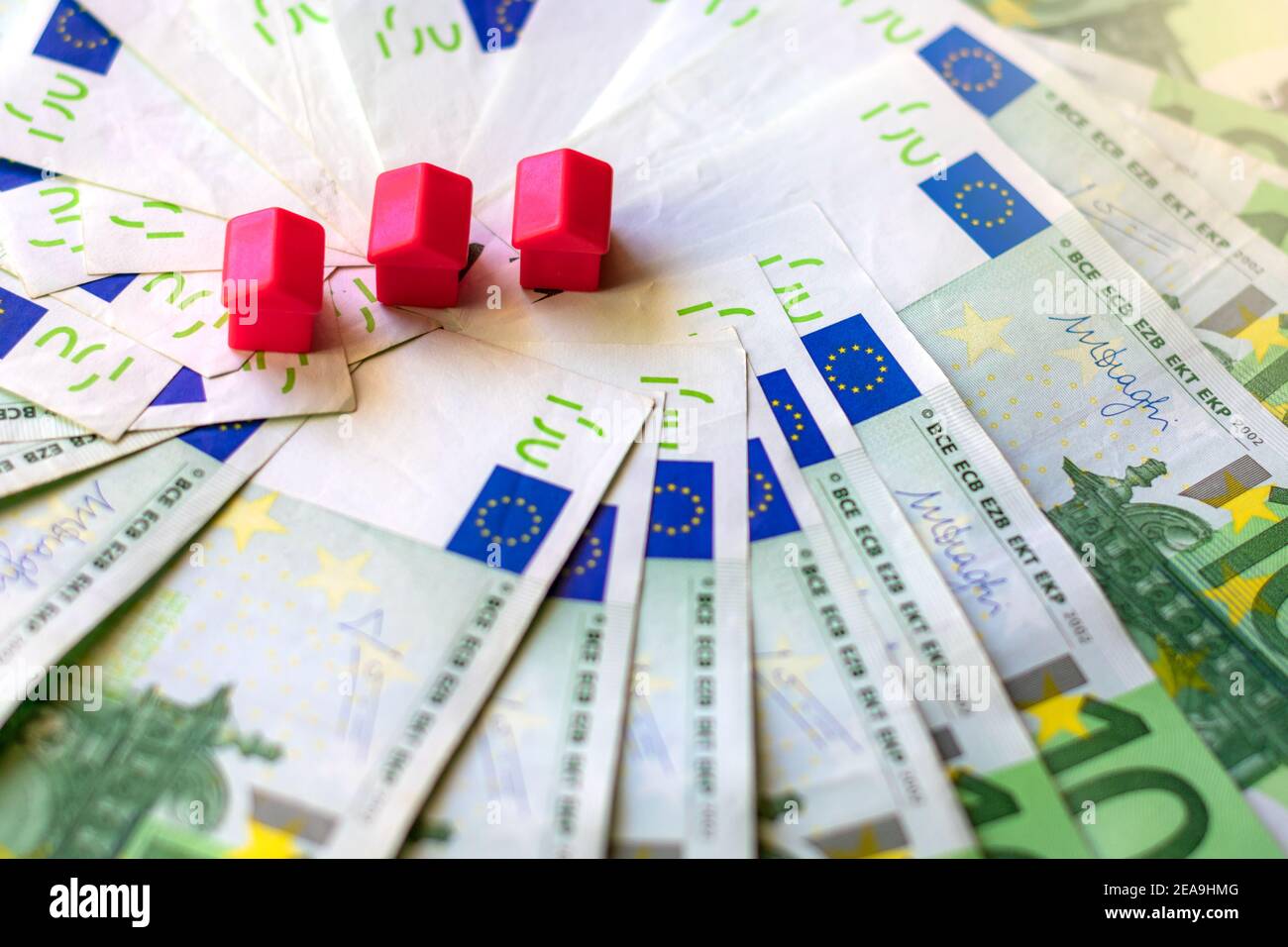 100 euro bills and miniature houses, concept of the cost of buying a