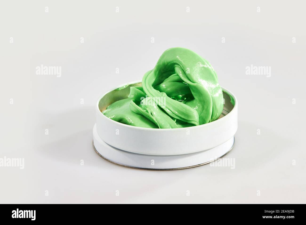 Green toy called smart gum in a tin can. Stretchable antistress toy for relaxation. Gum for hands. Stock Photo