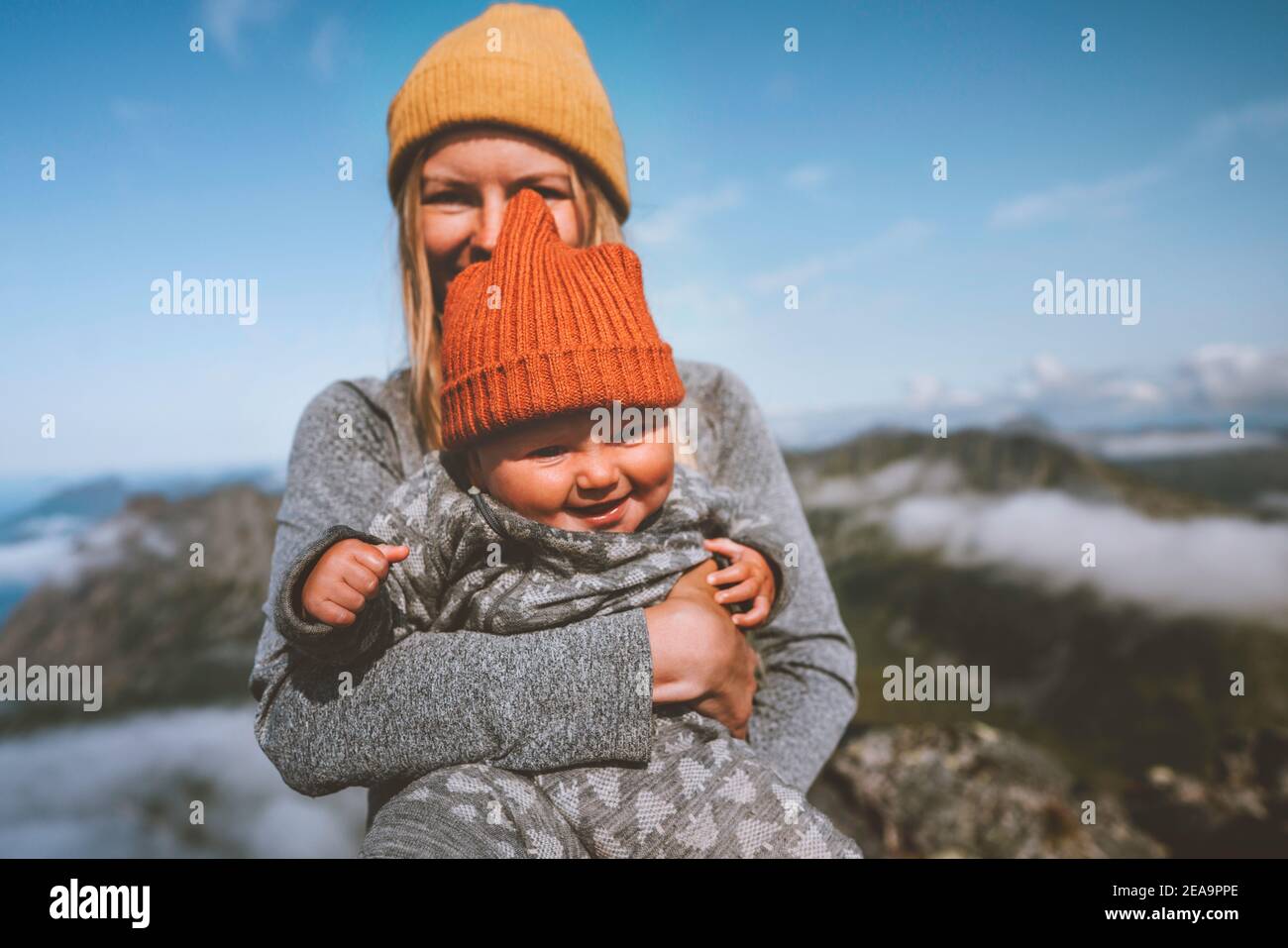 Family lifestyle baby with mother traveling together active healthy lifestyle vacation woman hiking with infant child in mountains of Norway Stock Photo