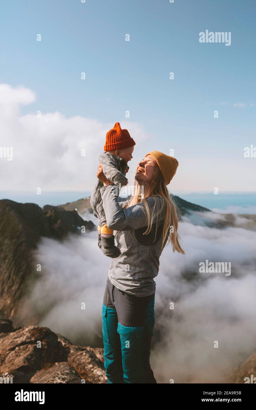 Mother with baby on mountain top family hiking in mountains vacation outdoor cheerful woman with child healthy lifestyle journey in Norway happy emoti Stock Photo