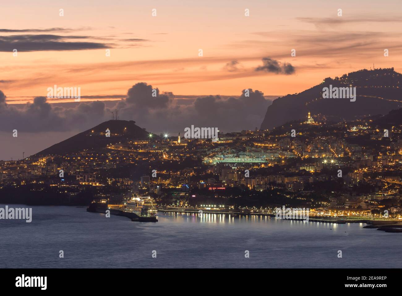 Funchal, the capital of Madeira at sunset and with illuminated houses, including a harbor and a cruise ship. Stock Photo