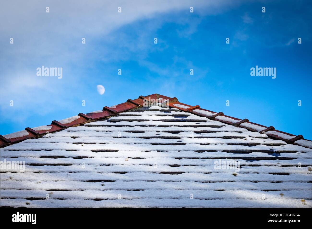 Graphic image of snowy rooftop with the moon behind taken early morning. Stock Photo