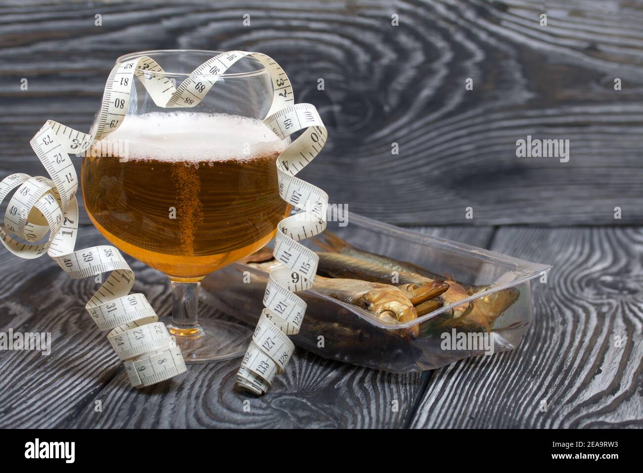 Beer in a glass and smoked fish. Nearby is a measuring tape. On pine boards.  A day without diets Stock Photo - Alamy