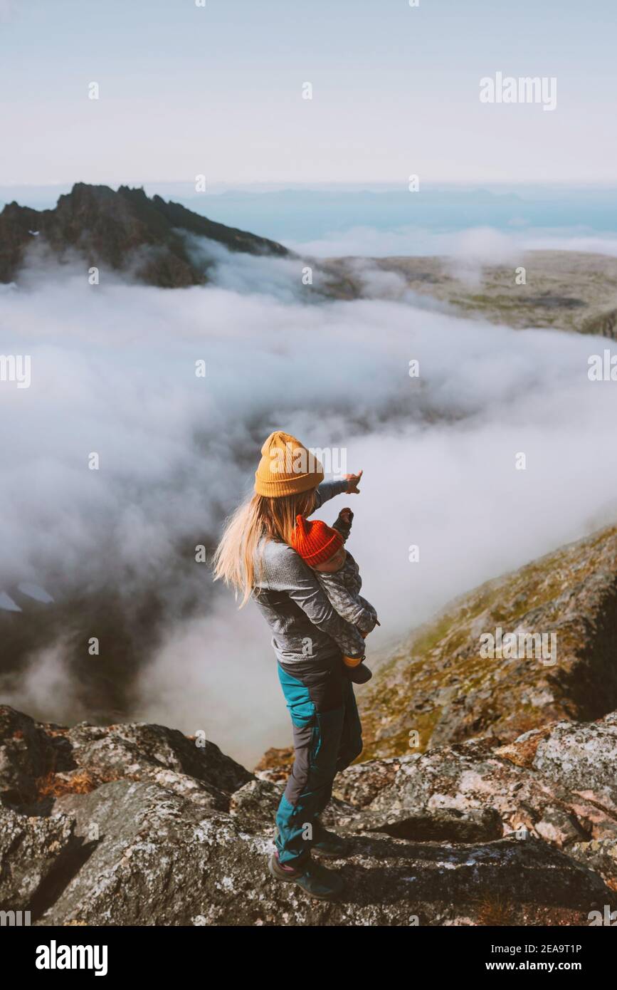 Mother hiking with baby in mountains family vacation travel outdoor woman with child together on the top healthy lifestyle weekend trip in Norway Stock Photo