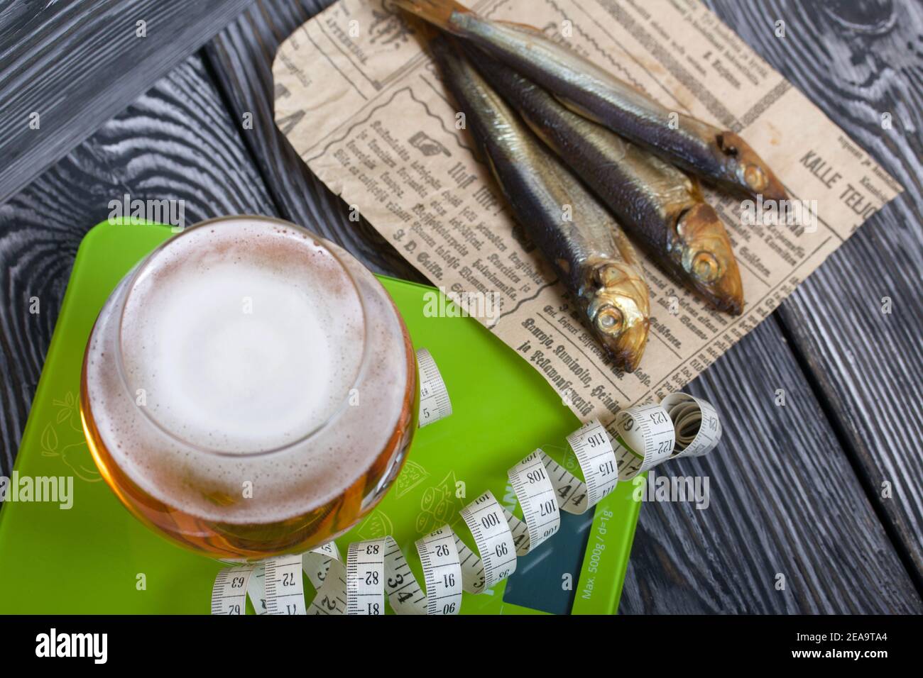 Beer in a glass and smoked fish. Scales and measuring tape are nearby