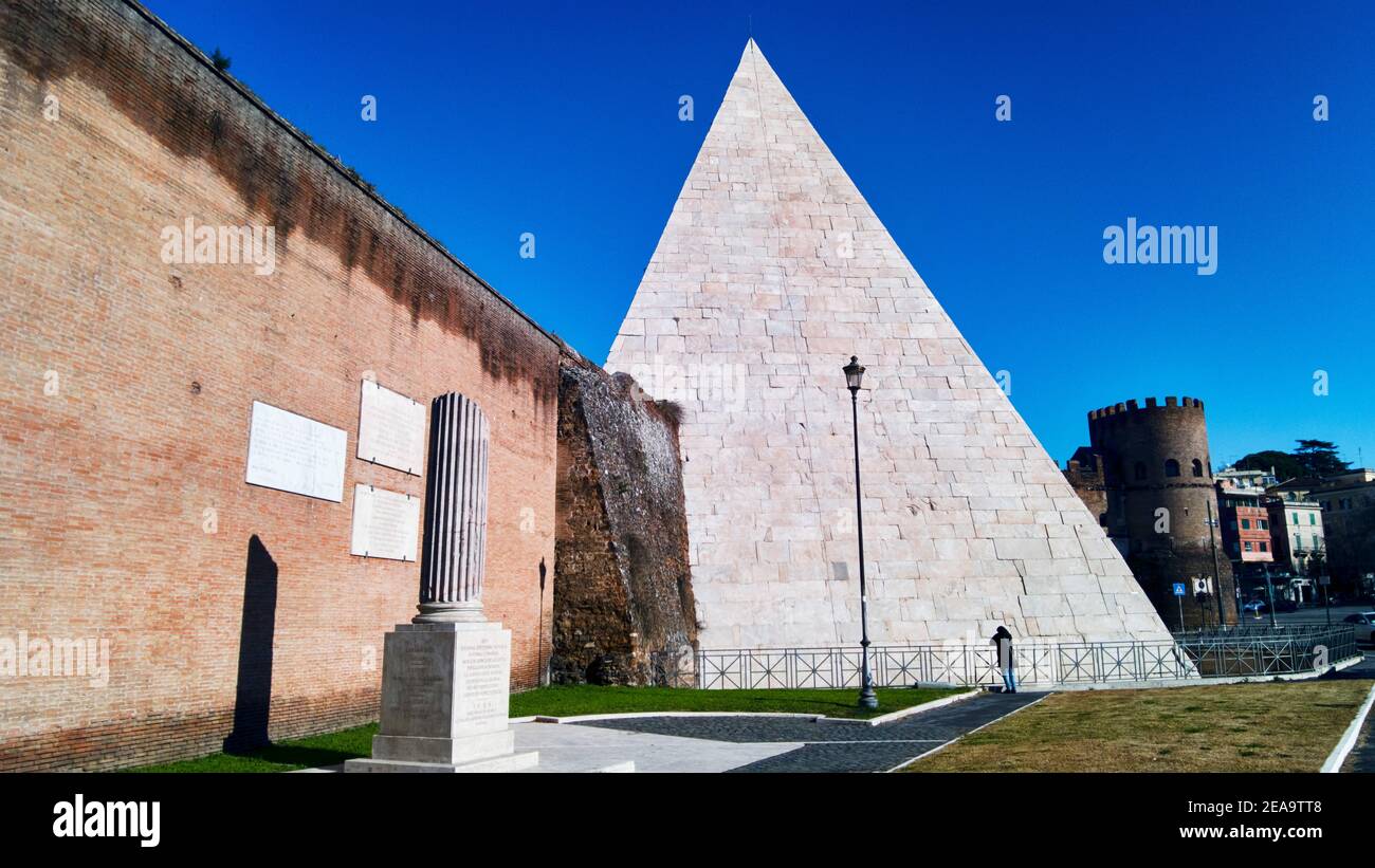 Rome street view at Ostiense Square with ancient and well preserved Pyramid Cestia in latin Pyramid of Caio Cestio with ancient urban wall and city sk Stock Photo