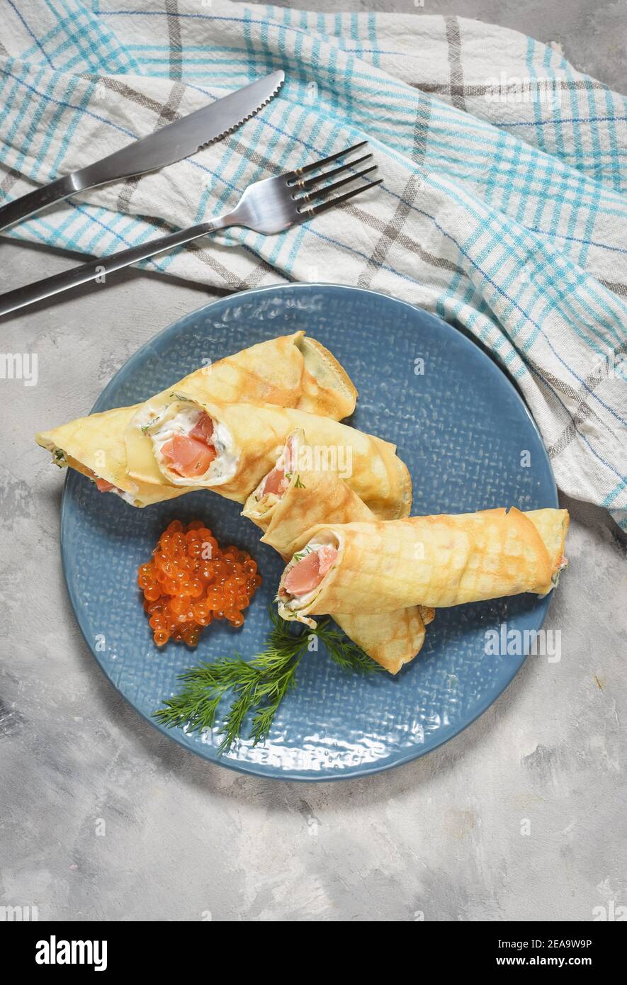 Delicious breakfast - crepes with smoked salmon, sour cream and caviarch on concrete background. Top view Stock Photo