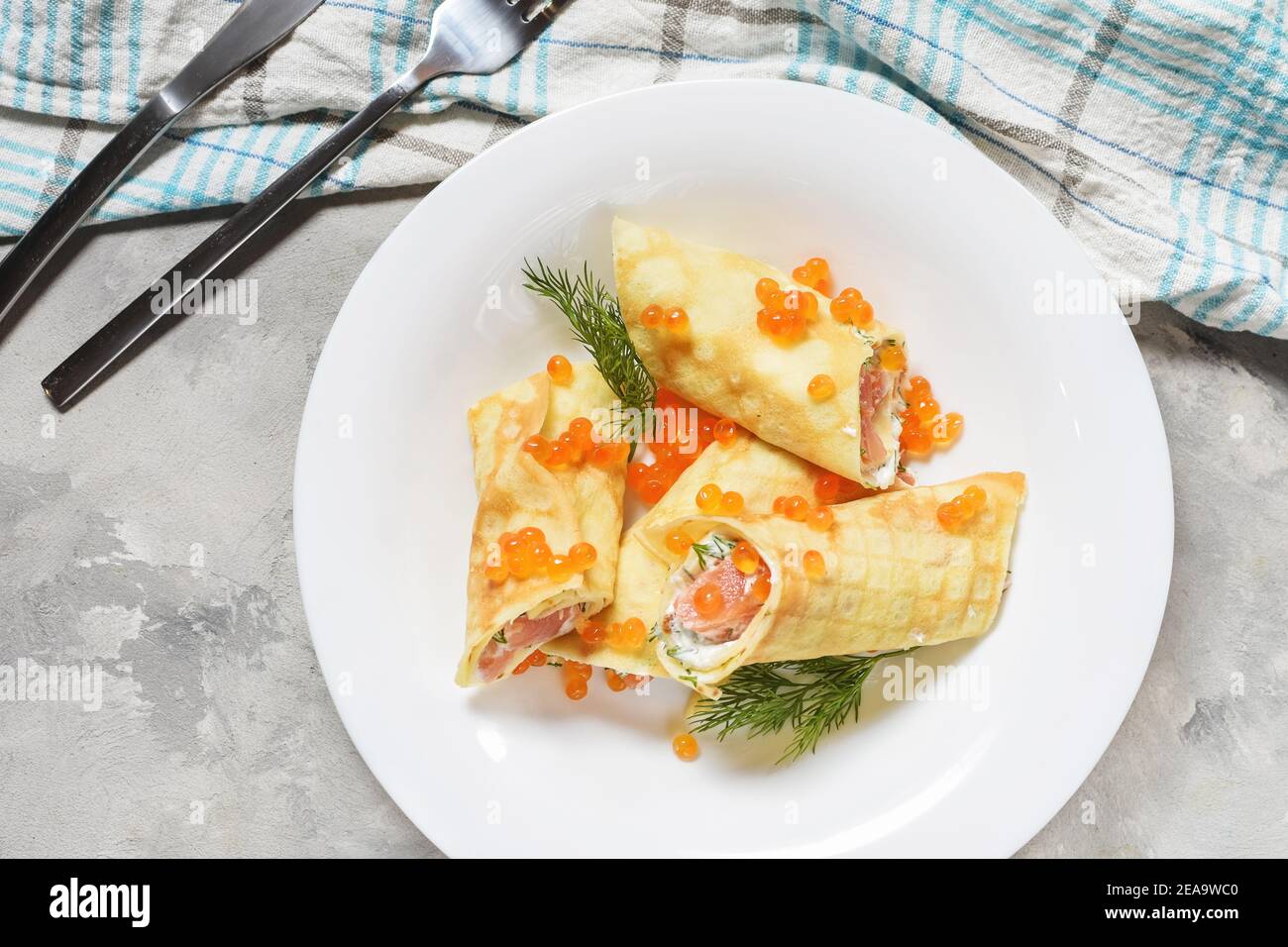 Delicious breakfast - crepes with smoked salmon, sour cream and caviarch on concrete background. Top view Stock Photo