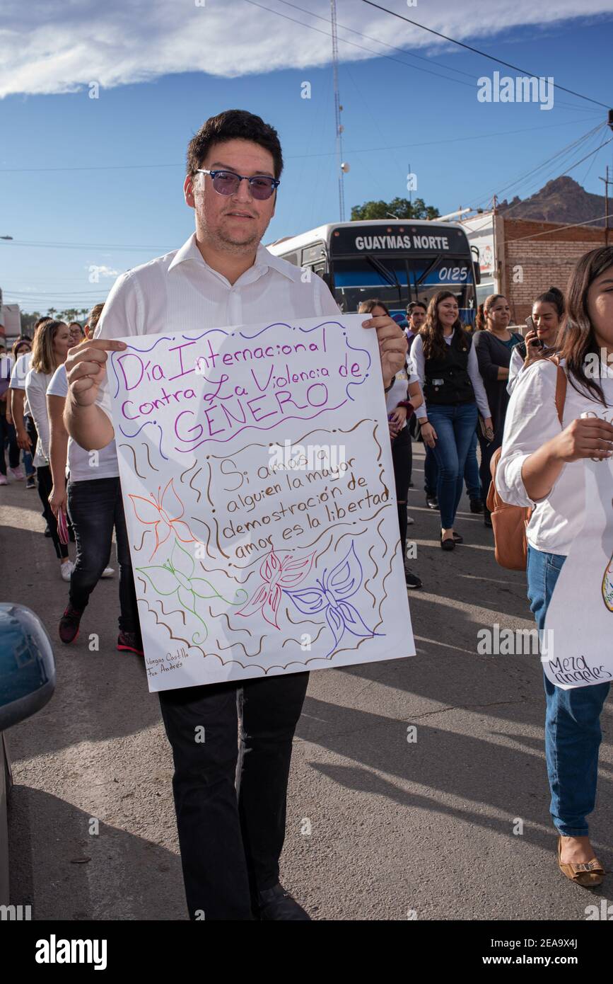 A young man walking in a demonstration to protest violence against women poses holding his sign. Stock Photo