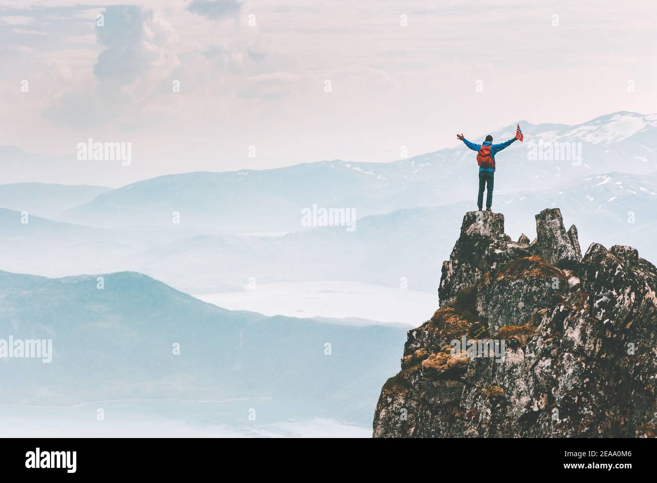 Man climber on mountain cliff summit traveling hike in Norway adventure vacations outdoor extreme activity healthy lifestyle traveler success raised h Stock Photo