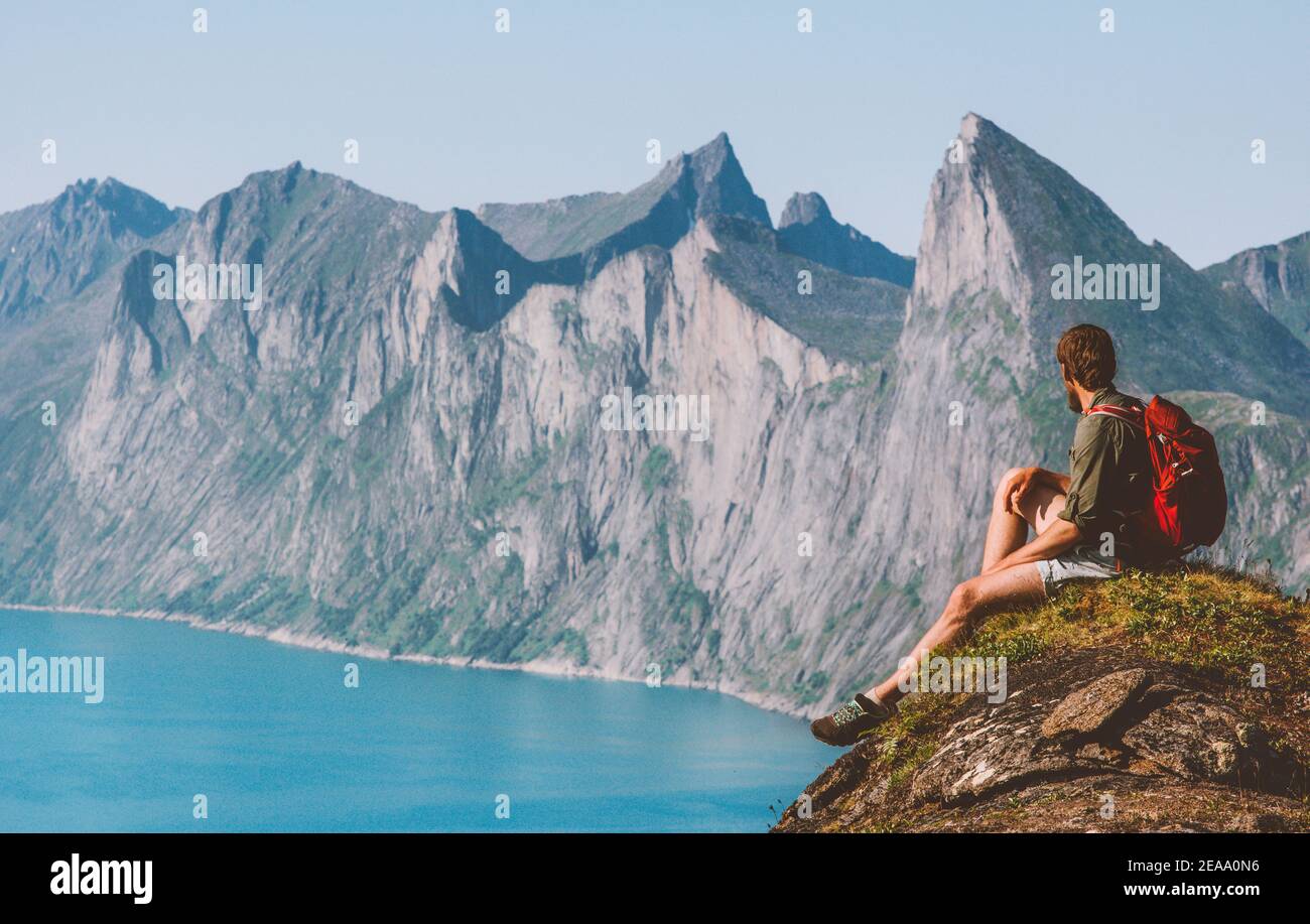Man traveler sitting on cliff mountain travel vacations in Norway backpacker enjoying landscape adventure lifestyle outdoor activity Senja islands Stock Photo