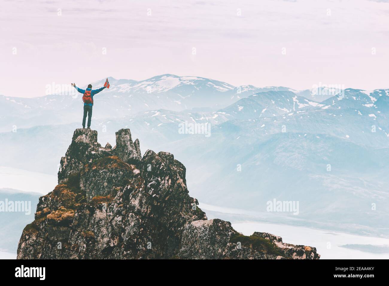 Man climbing on mountain top adventure travel outdoor extreme active lifestyle vacation tour hiking in Norway success raised hands Husfjellet peak Stock Photo