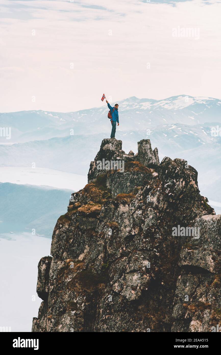 Man standing on mountain cliff summit travel adventure climbing outdoor extreme active lifestyle vacation trip hiking in Norway Husfjellet peak Stock Photo
