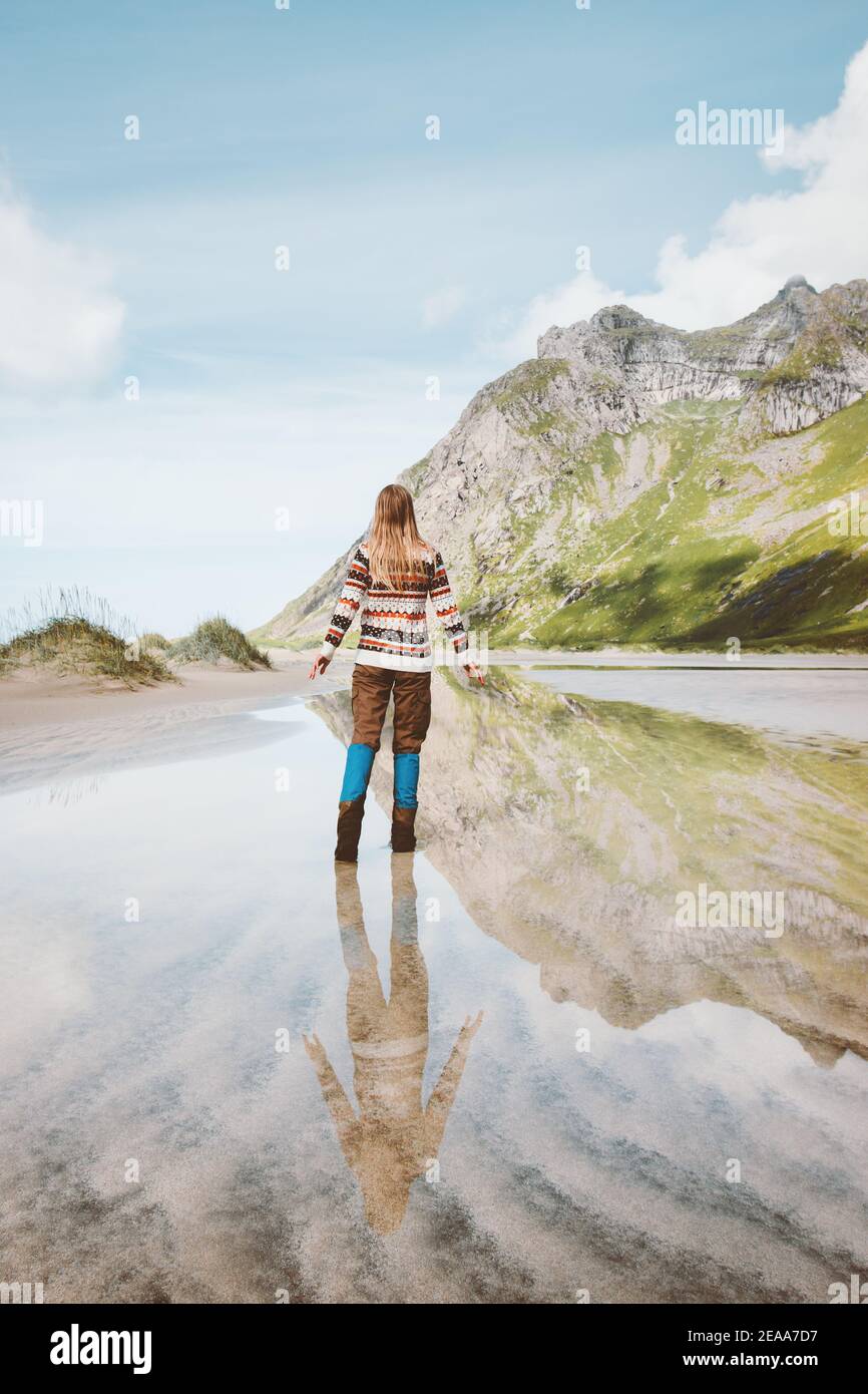 Woman walking alone outdoor water reflection mountain landscape travel in Norway outdoor adventure active healthy lifestyle weekend getaway Stock Photo