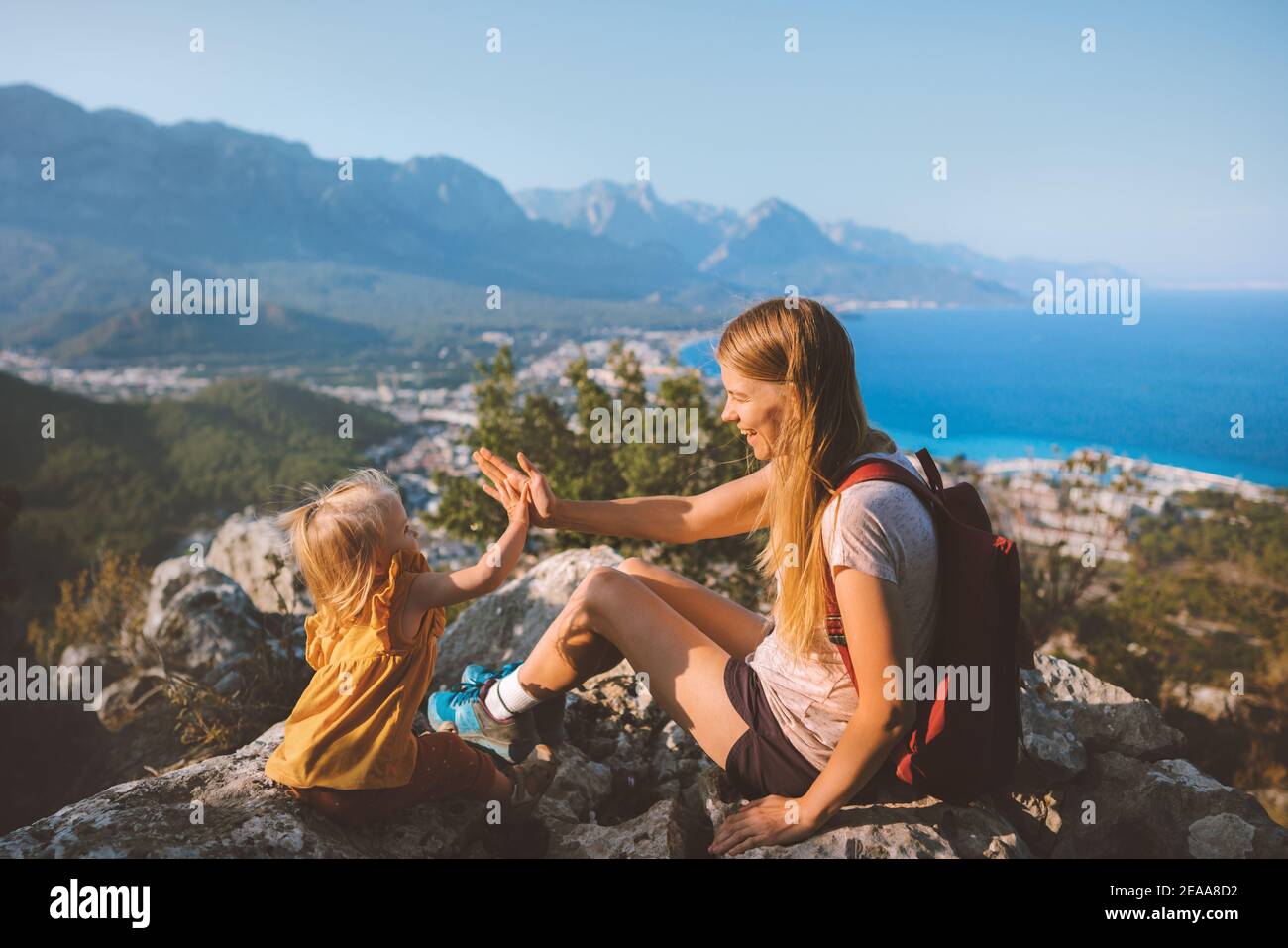 Family mother with daughter traveling in Turkey active vacation mom and child hiking together high five hands fun on mountain summit healthy lifestyle Stock Photo