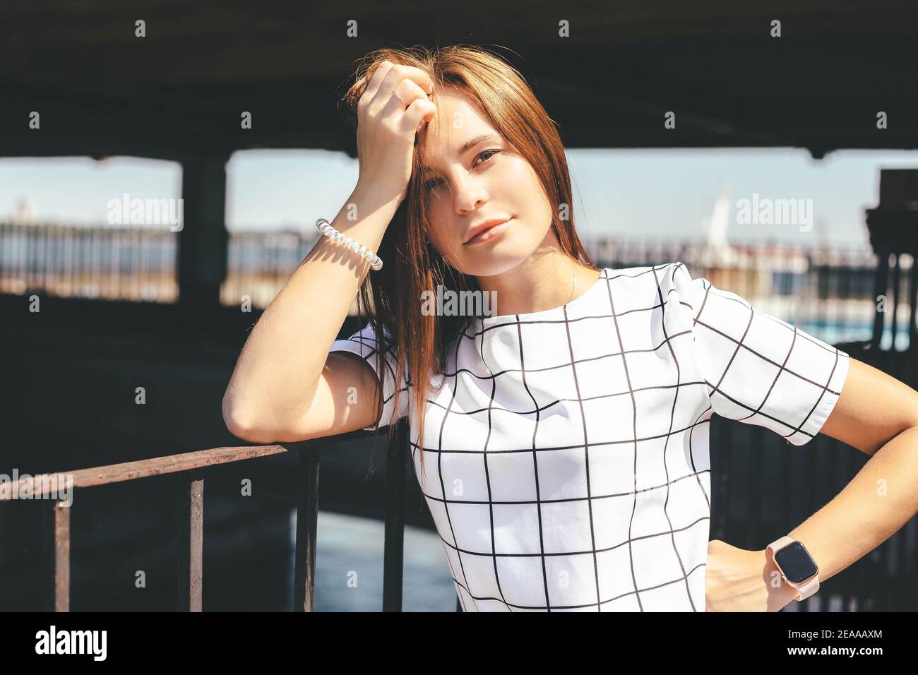 Pretty woman leaning on metal fence at sunny summer day. Urban lifestyle concept Stock Photo