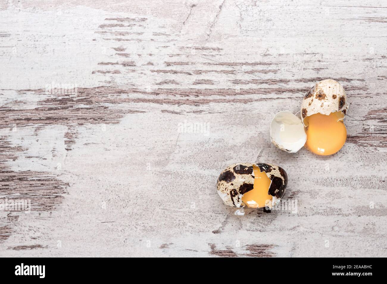 Two broken quail eggs on wooden table. Copy space, top view Stock Photo