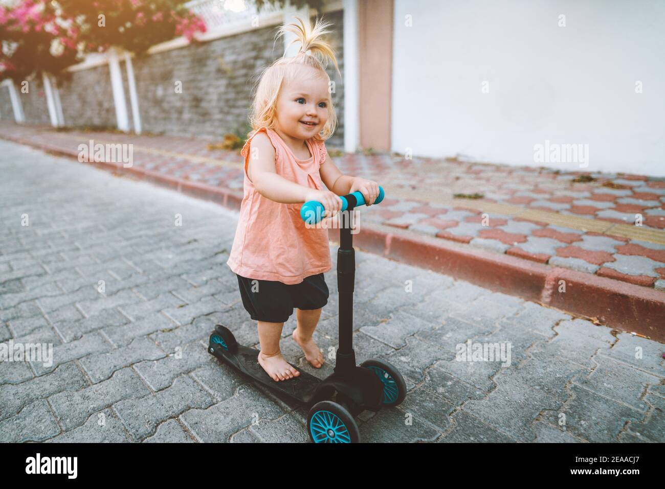 Baby girl riding scooter in city happy child 1 year old healthy lifestyle family fun activity outdoor Stock Photo