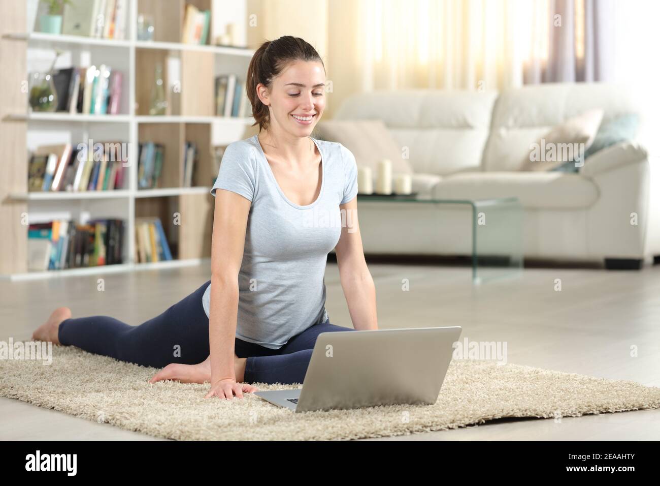 Happy woman e-learning online yoga tutorial on the floor at home Stock Photo