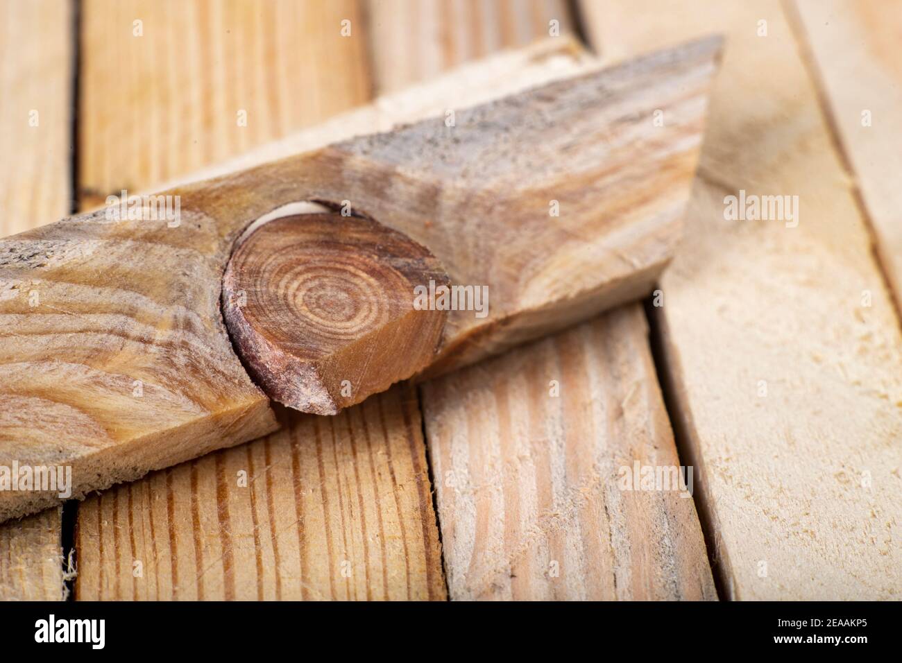 A hard knot in a raw slat. A knot from a piece of wood. Light background. Stock Photo