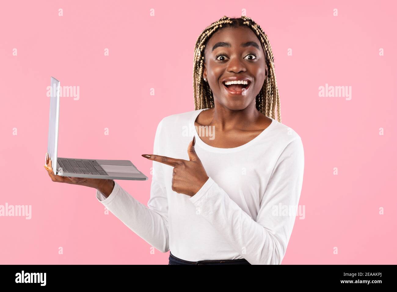 Black young woman holding laptop and pointing at screen Stock Photo - Alamy