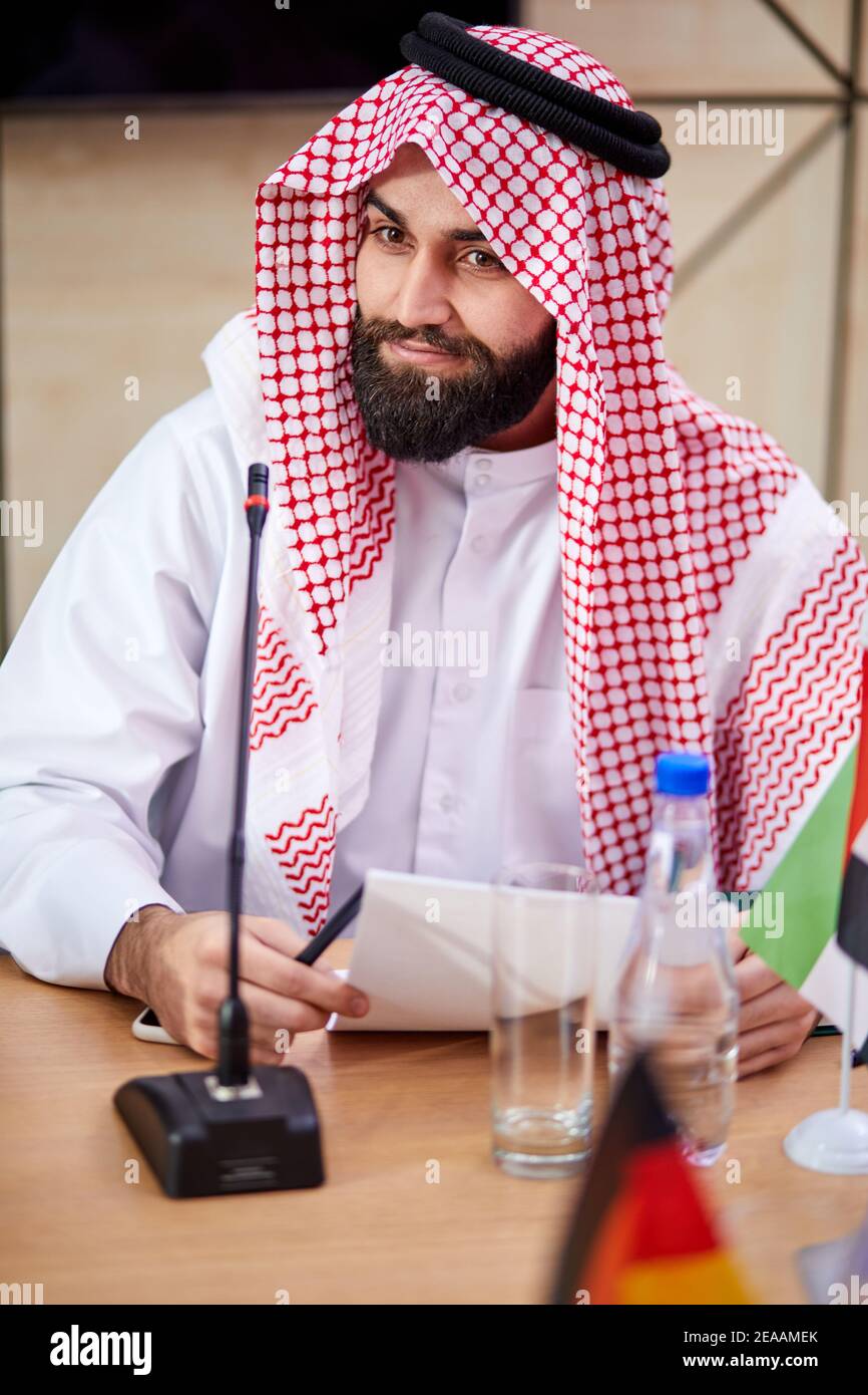 young arabic sheikh man wearing traditional emirates clothes sits at desk  on business meeting, male saudi arab arabic business muslim traditional  shei Stock Photo - Alamy