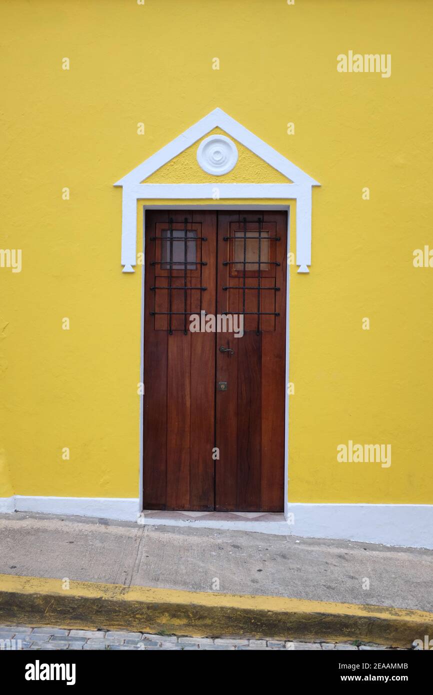 Old wood door on a bright yellow building in the Caribbean Stock Photo